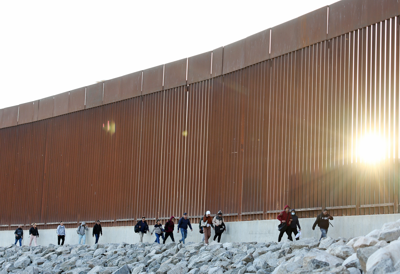 Immigrants seeking asylum in the United States walk along the border fence after crossing into Arizona from Mexico in May 2023